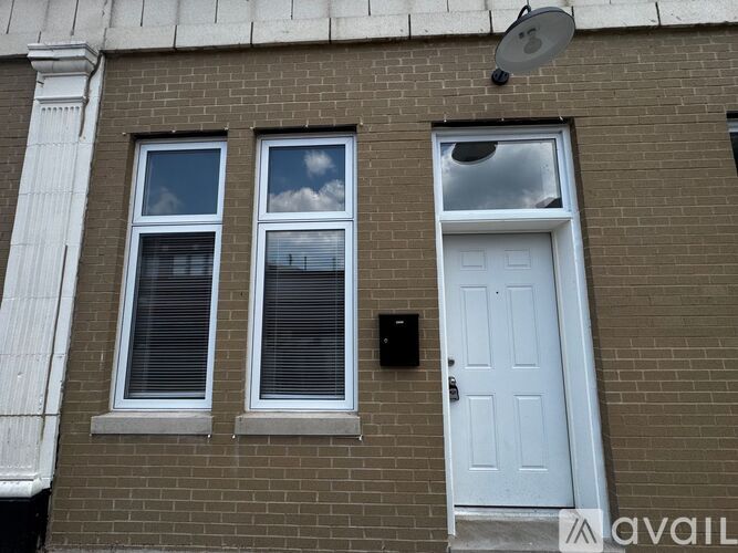 A white door is on the right side of a brick building.