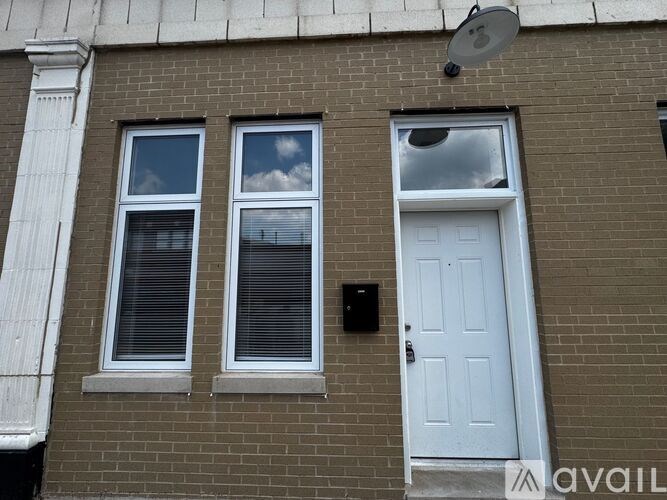 A white door is on the right side of a brick building.