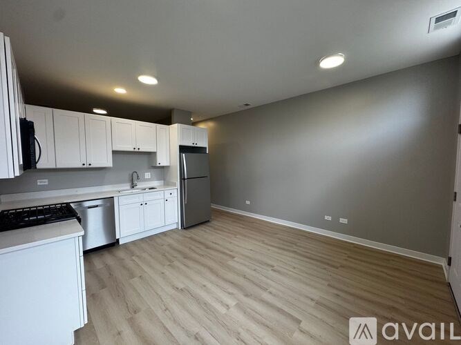A kitchen with white cabinets and a wooden floor.