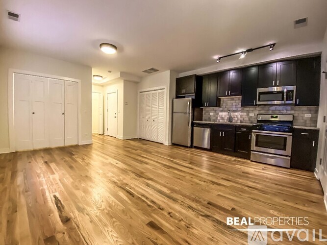 A room with wooden flooring and two windows.