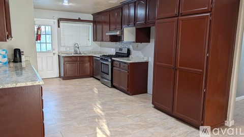 A kitchen with brown cabinets and a tiled floor.