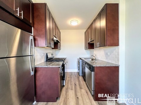 A kitchen with a stainless steel refrigerator and wooden cabinets.