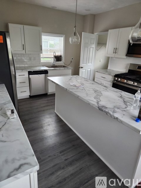 A kitchen with white cabinets and a marble countertop.