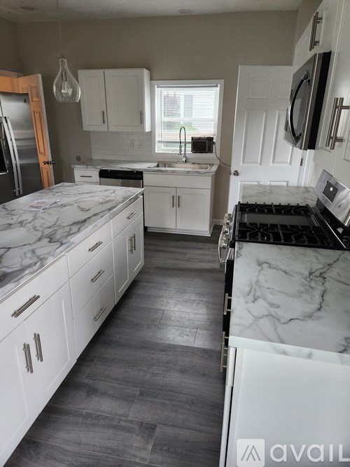 A kitchen with white cabinets and marble countertops.