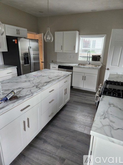 A kitchen with white cabinets and a marble countertop.