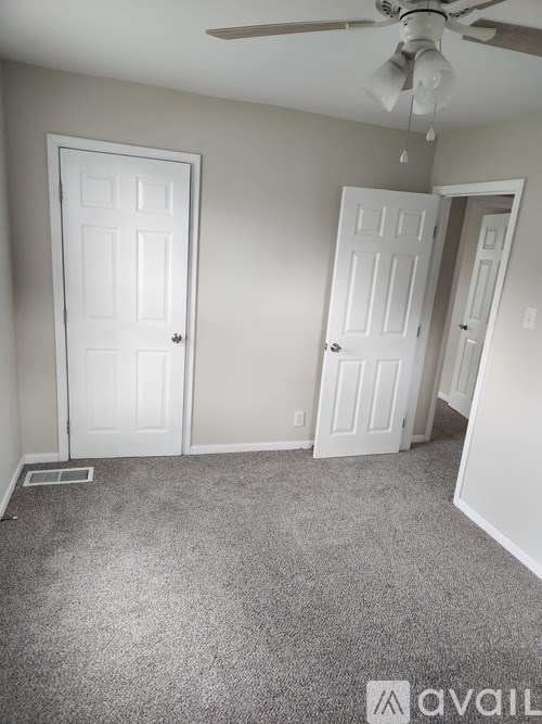A room with a carpeted floor and a ceiling fan.