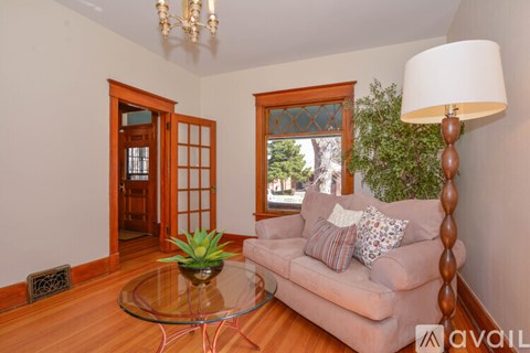A living room with a glass table and a couch with a plant on it.