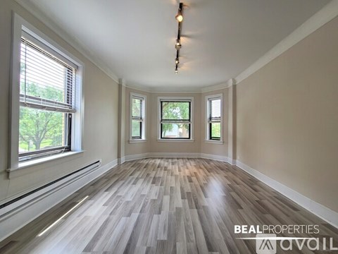 A room with wooden flooring and three windows.