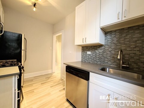A kitchen with white cabinets and a black fridge.
