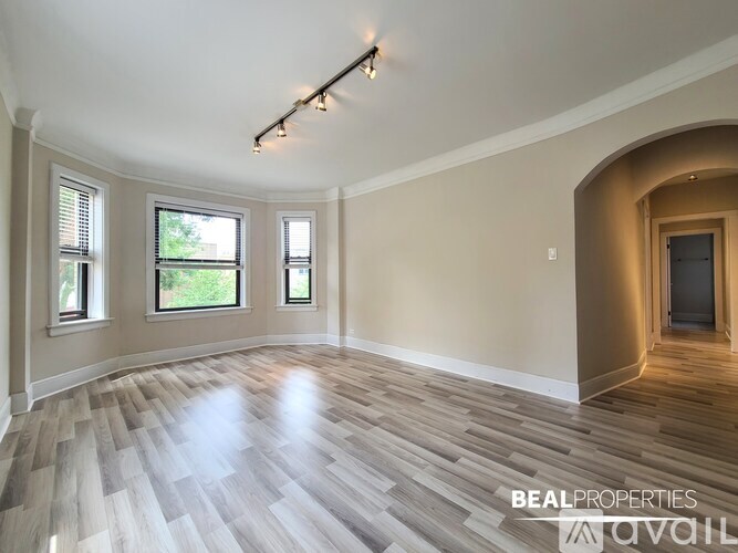 A spacious room with wooden flooring and a large arched doorway.