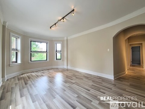 A spacious room with wooden flooring and a large arched doorway.