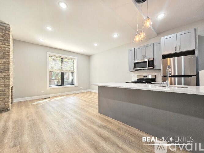 A spacious kitchen with a brick wall and wooden flooring.