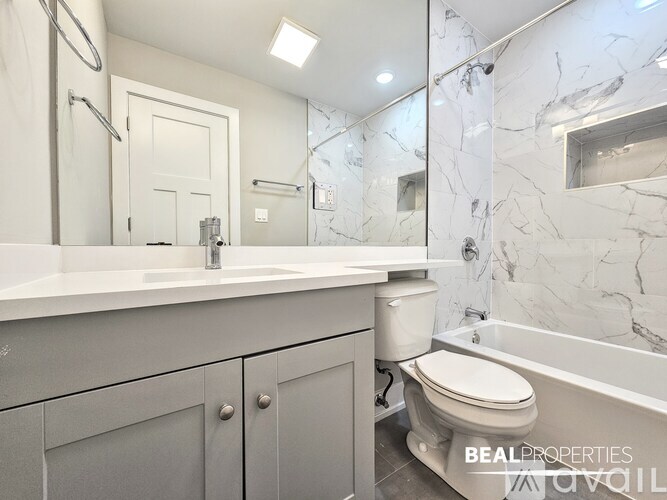 A bathroom with a marble tile wall and a white bathtub.