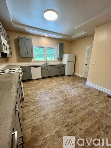 A kitchen with wooden flooring and a white stove top oven.