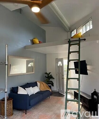 A living room with a blue couch and a green ladder.