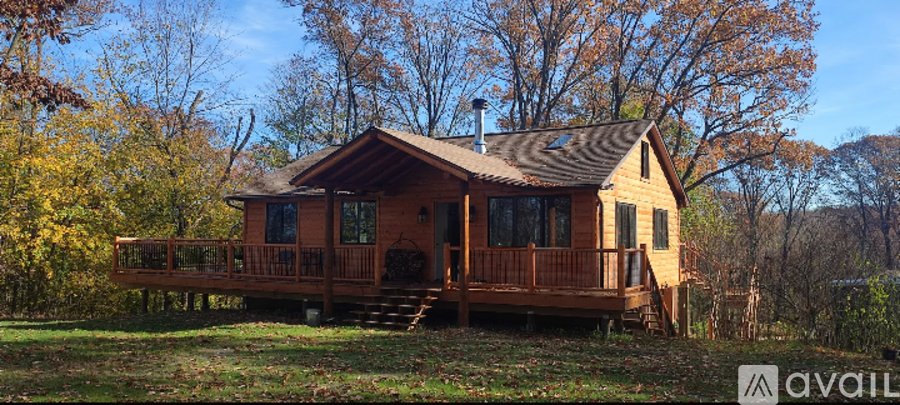 A small wooden cabin with a porch is surrounded by trees.