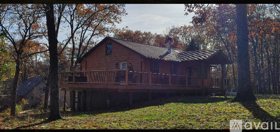 A wooden house with a porch surrounded by trees.