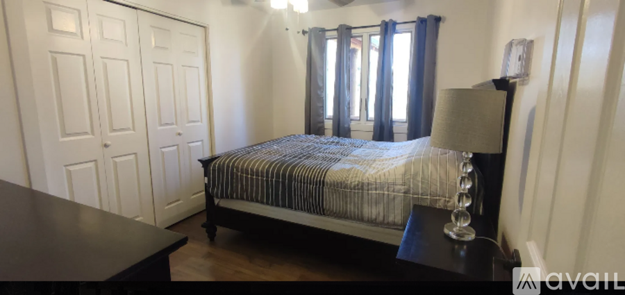 A bedroom with a bed, nightstand, and a window with curtains.
