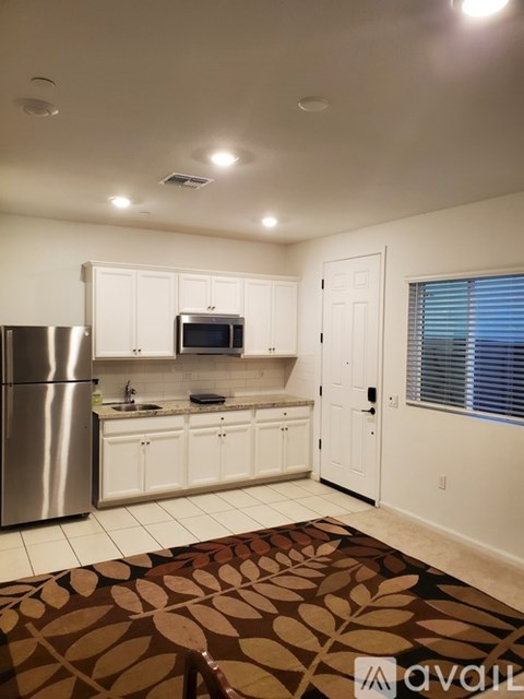 A kitchen with white cabinets and a stainless steel refrigerator.