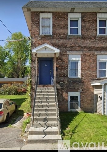 A brick house with a blue door and a car parked in front.