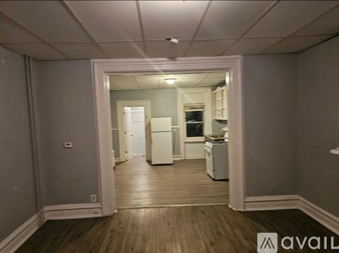 A kitchen with white appliances and wooden floors.