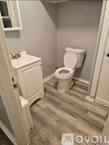 A white toilet in a bathroom with wood flooring.