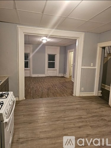 A room with a white stove and wooden flooring.