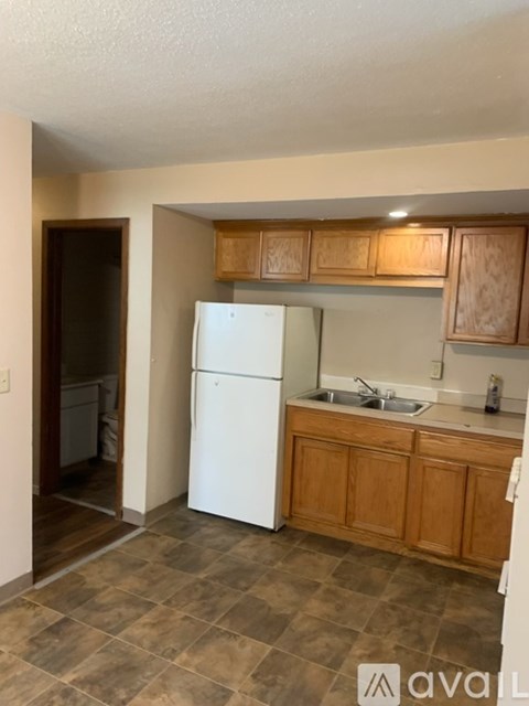 A kitchen with a white refrigerator and wooden cabinets.