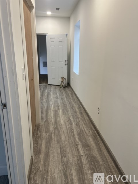 A hallway with wood flooring and white walls.