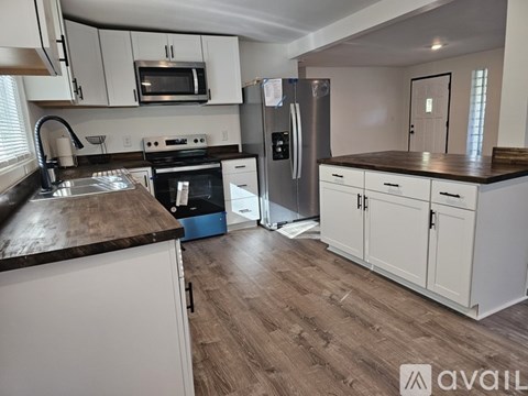 A kitchen with white cabinets and a wooden countertop.