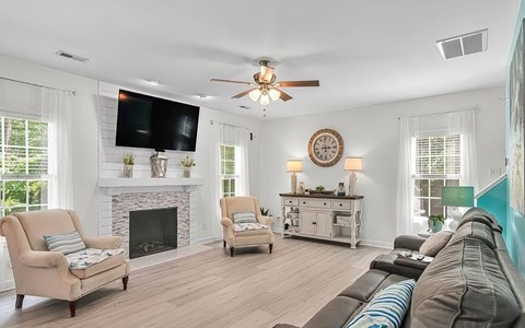A living room with a fireplace and a television mounted above it.