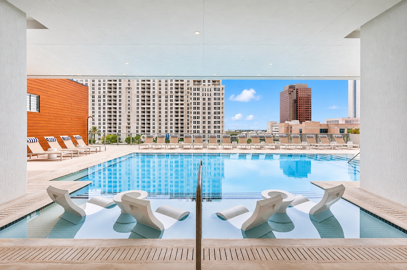 A pool with a white diving board and a building in the background.