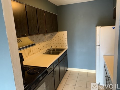 A kitchen with black cabinets and a white fridge.