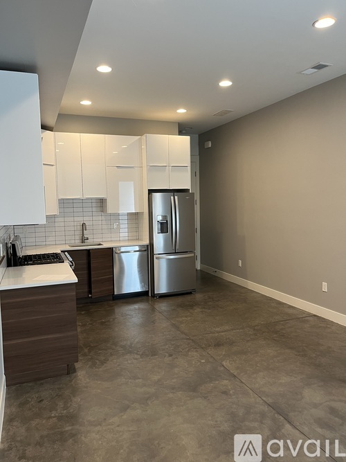 A kitchen with a refrigerator, sink, and cabinets.