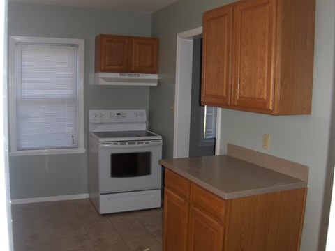 A kitchen with a white stove and wooden cabinets.