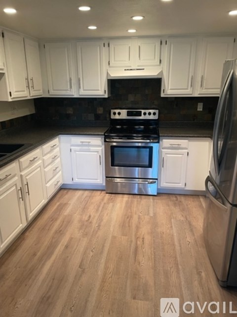 A kitchen with white cabinets and a stainless steel refrigerator.