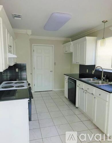 A kitchen with white cabinets and black countertops.