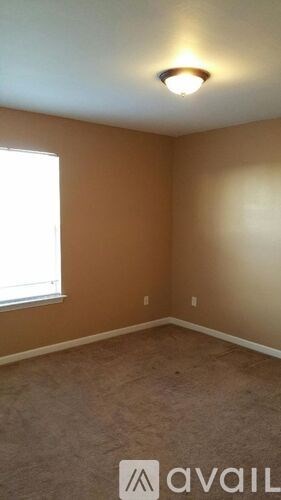 A room with a window and a carpeted floor.