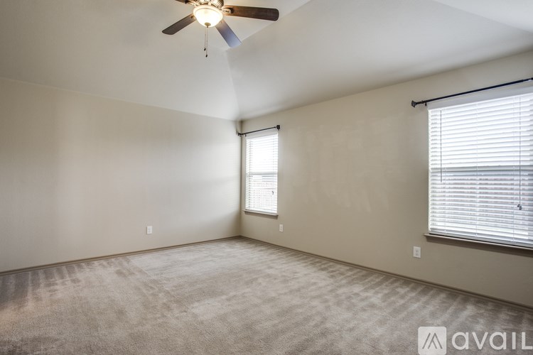 A room with a ceiling fan and two windows with blinds.
