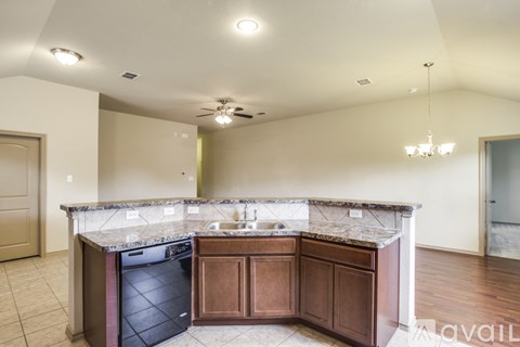 A kitchen with a black dishwasher and brown cabinets.