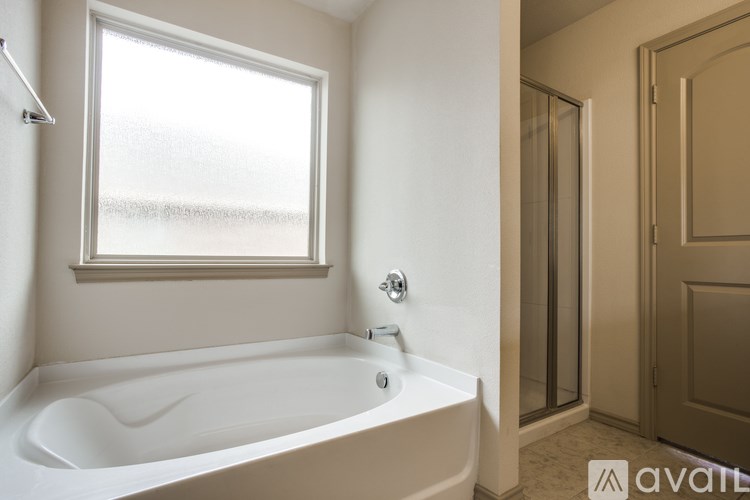 A white bathtub with a window above it in a bathroom.