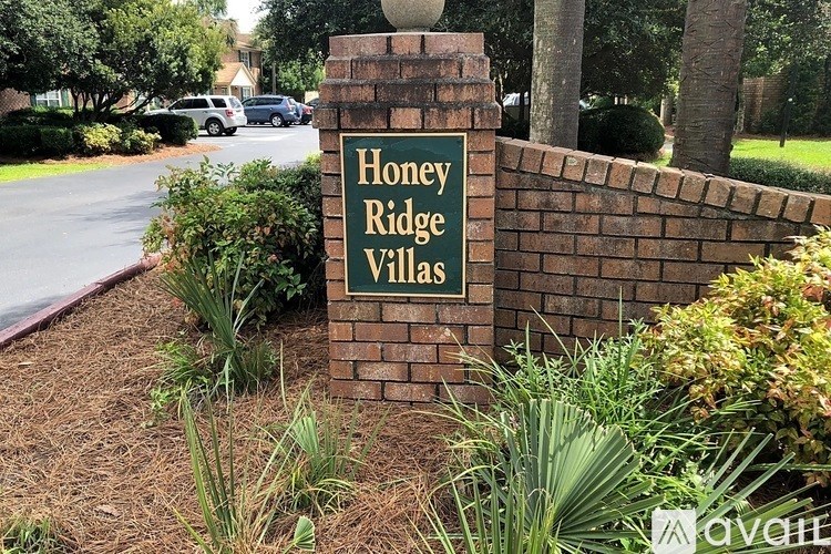 A sign that says Honey Ridge Villas stands in front of a brick wall.