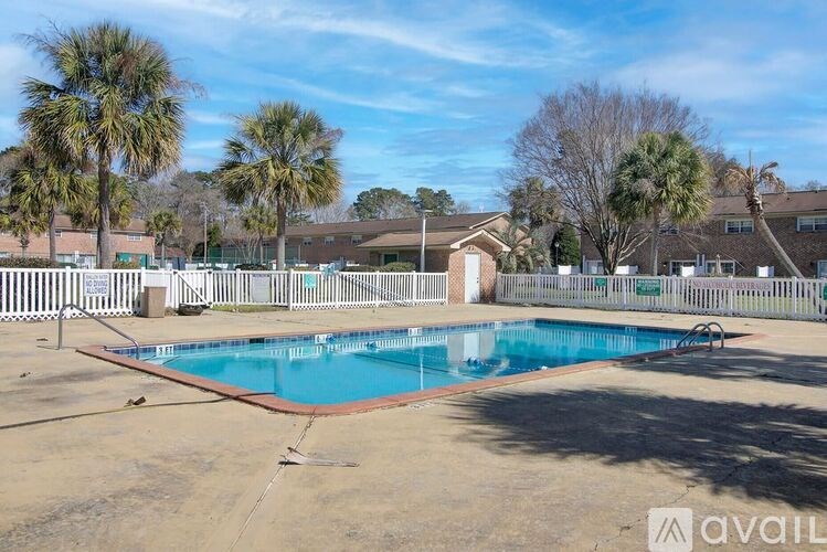 A pool surrounded by a fence with trees in the background.