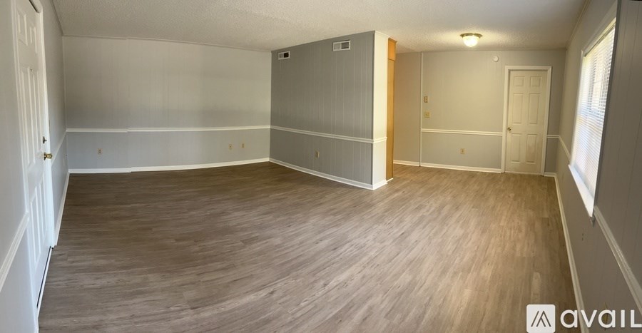 A spacious room with wooden flooring and white walls.