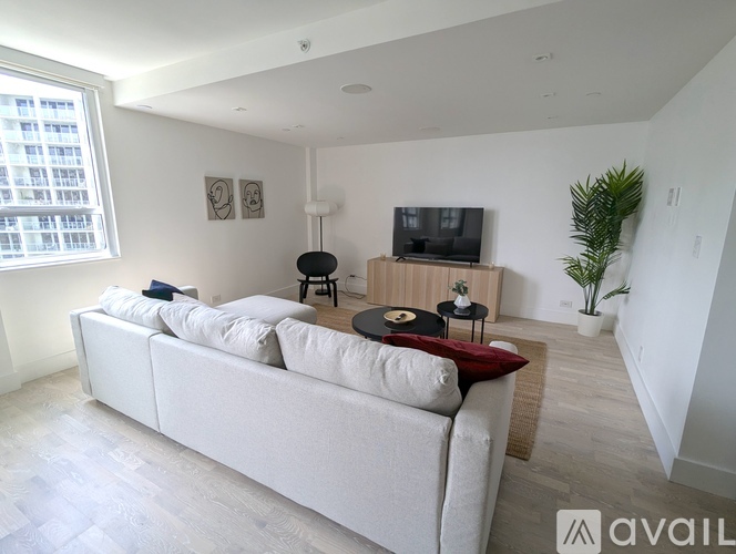 A living room with a white couch and a television on a wooden stand.