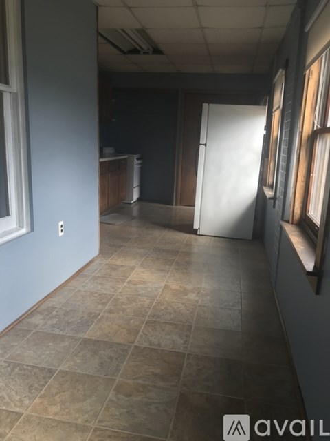 A tiled kitchen area with a white fridge and a window.