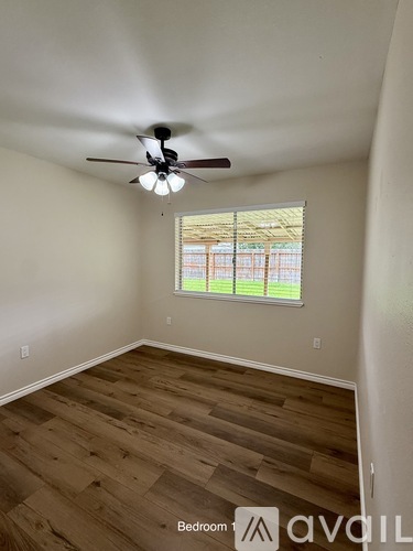 A bedroom with a ceiling fan and wooden flooring.