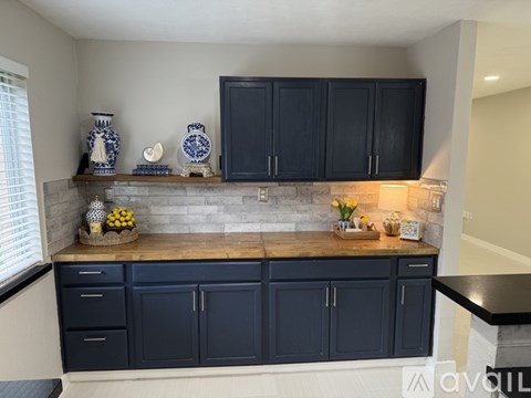 A kitchen with dark blue cabinets and a stone backsplash.