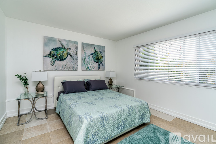 A bedroom with a bed, two lamps, and two paintings on the wall.