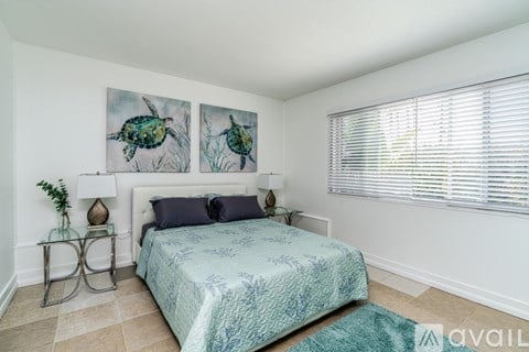 A bedroom with a bed, two lamps, and two paintings on the wall.